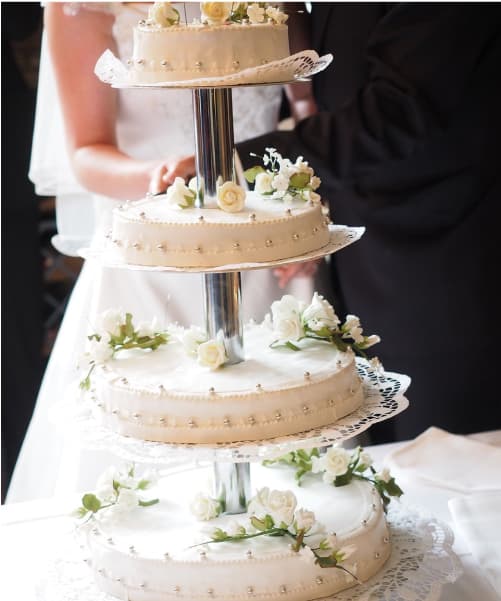 4 tiered wedding cake with flowers placed on each tier.