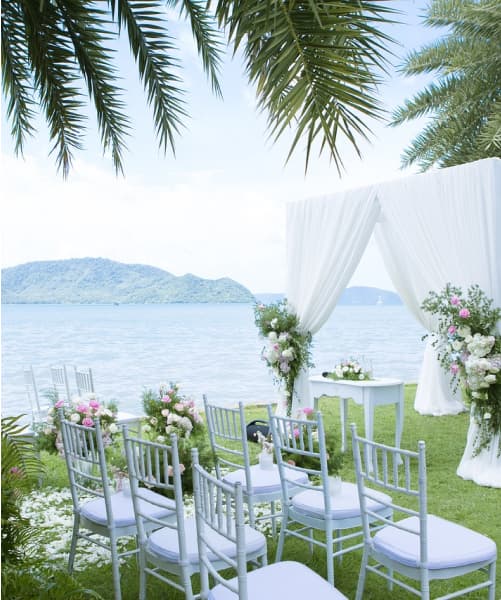 Joshua and Piper's Outdoor wedding venue with chairs arranged before a cloth and floral covered pathway.